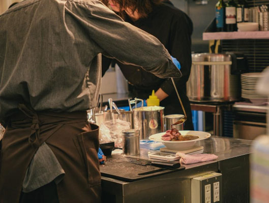 A chef plating a dish with fresh local produce in a professional kitchen